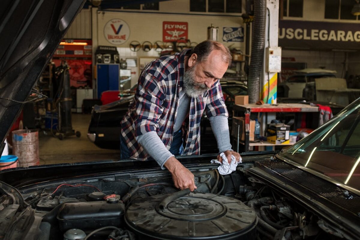 Carrosserie Bras Bearded mechanic working on engine repair in an auto repair shop garage with a focus on hands-on car service.